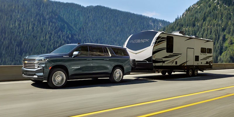 A black Suburban towing a White Trailor