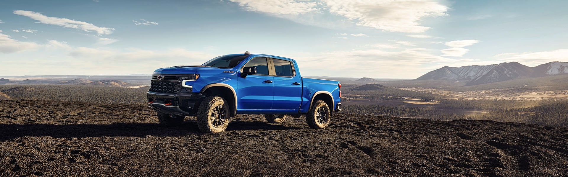 A blue Silverado truck standing on ground where have a soil