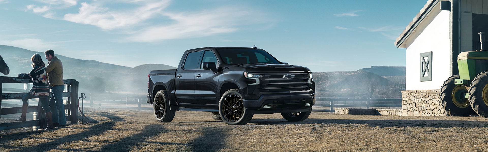 A black Silverado stands near farm house