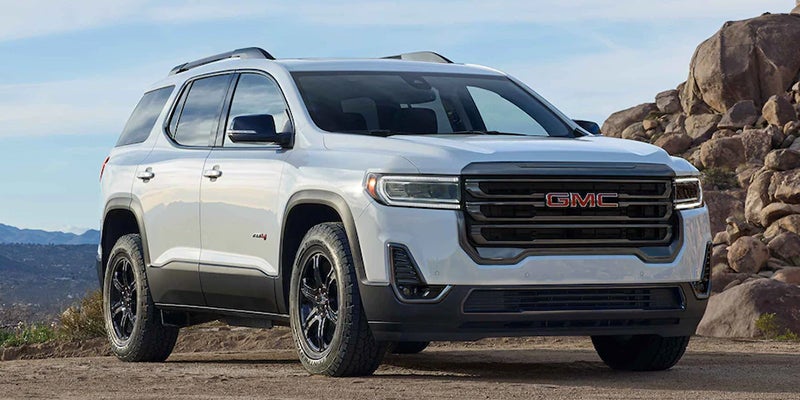 A white Acadia Parked on hills ground near rocky front right side view