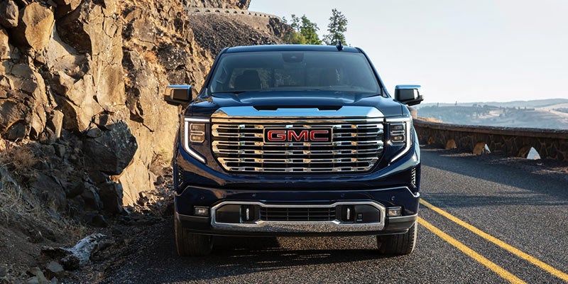 A GMC Sierra parked one side of road between mountains