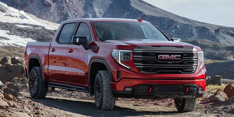 A red GMC Sierra driving rough roads near hills
