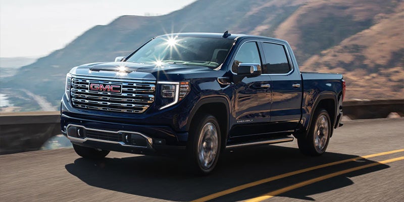Black Sierra truck running on road between mountains